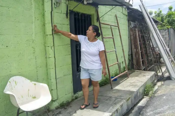 Cindy Monterrosa dice que la pared de su casa además de agrietada se está hundiendo, ella y su familia no pueden permanecer en la sala de la vivienda porque está hueca. / Lisbeth Ayala. 