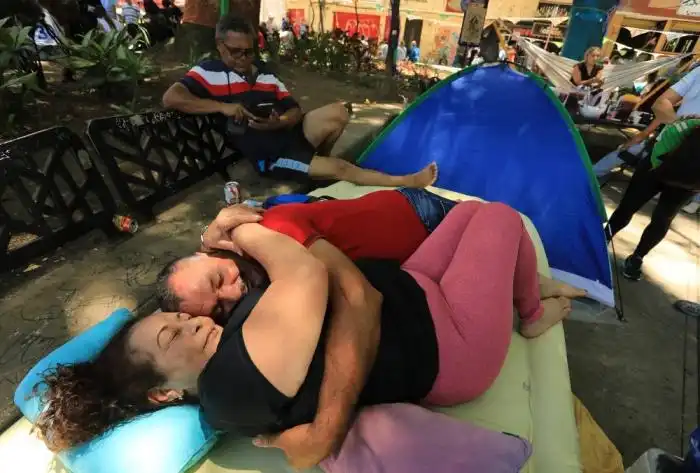 Una pareja finge estar dormida durante la celebración del Día Mundial de la Pereza en Itagüí, Colombia, el 18 de agosto de 2024. (Foto de JAIME SALDARRIAGA / AFP)