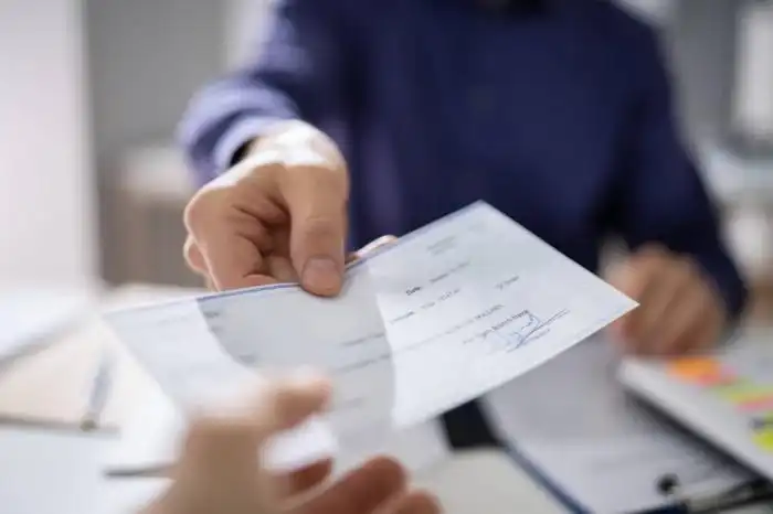 Los cheques son el segundo método más utilizado por los salvadoreños como sistema de pago, según el BCR. /DEM,image_description:Businessperson Hands Giving Cheque