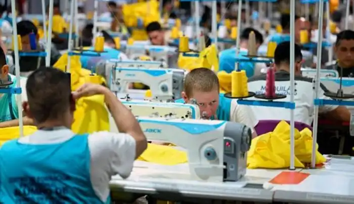 Un grupo de reos cosiendo uniformes.