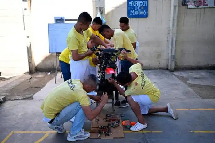 Un grupo de reos trabajan en reparar una motocicleta.
