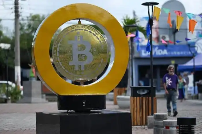 Un hombre pasa junto a un monumento de bitcoin en la Plaza Bitcoin en San Salvador. Según el Instituto de Opinión Pública (IUDOP), la adopción de bitcoin sigue siendo limitada en El Salvador a pesar de entrar en su tercer año como moneda legal. La ONG 