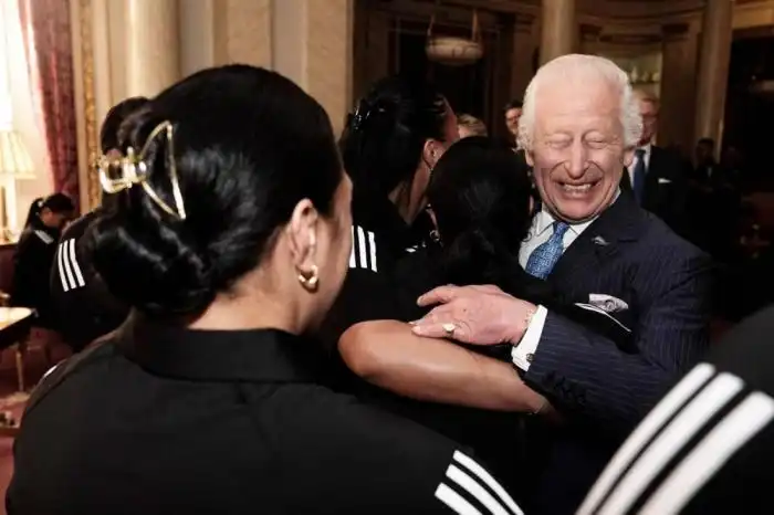 El rey Carlos III reacciona mientras es abrazado por miembros del equipo de rugby Black Ferns de Nueva Zelanda, en el Palacio de Buckingham, en el centro de Londres, el 11 de septiembre de 2024. Photo by Aaron Chown / POOL / AFP