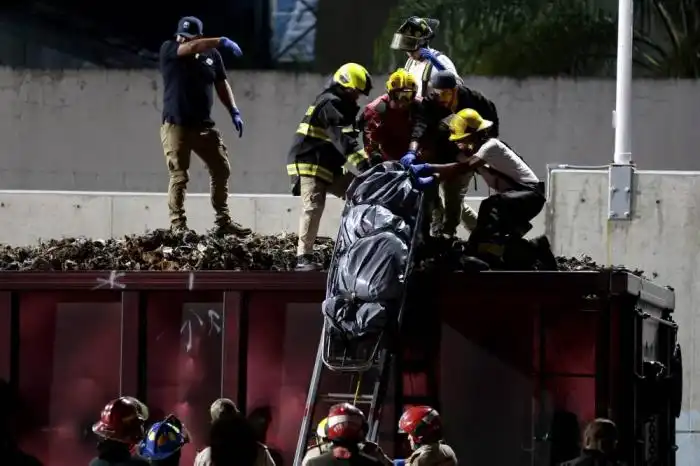 Un grupo de bomberos, junto a peritos forenses y miembros del Ministerio Público, recuperan uno de los tres cuerpos atados dentro de los vagones de un tren que cruza Guadalajara, estado de Jalisco, México. /AFP,image_description: