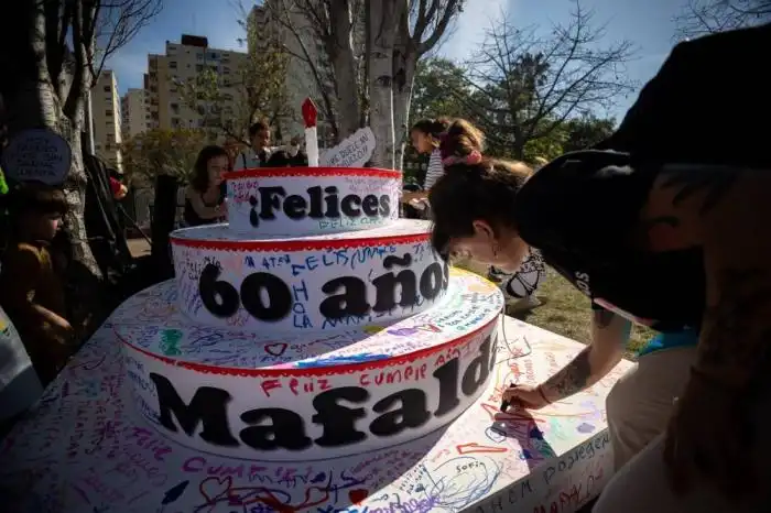 Una mujer escribe en una torta improvisada que dice 