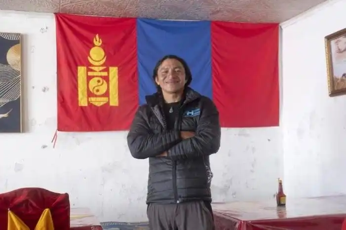 El salvadoreño José Gabriel Ruiz frente a una bandera de Mongolia, en su paso por Asia de la vuelta al mundo en bicicleta. / Cortesía de Marica van der Meer y Chepe Ruiz.