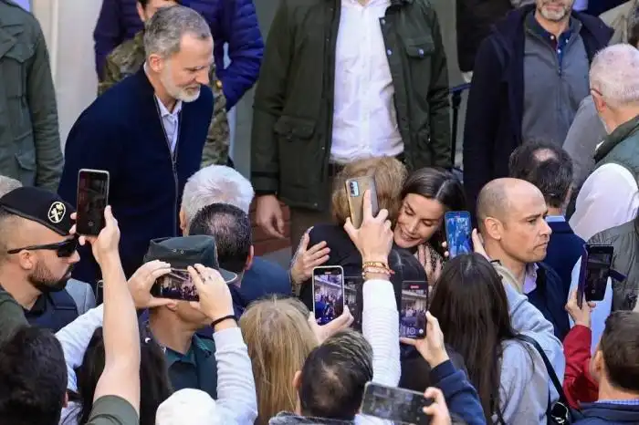 La reina Letizia de España (C) abraza a una mujer mientras el rey Felipe VI observa durante una visita a la localidad de Chiva, en la región de Valencia, al este de España, tras las devastadoras inundaciones mortales/ Foto José Jordán AFP.