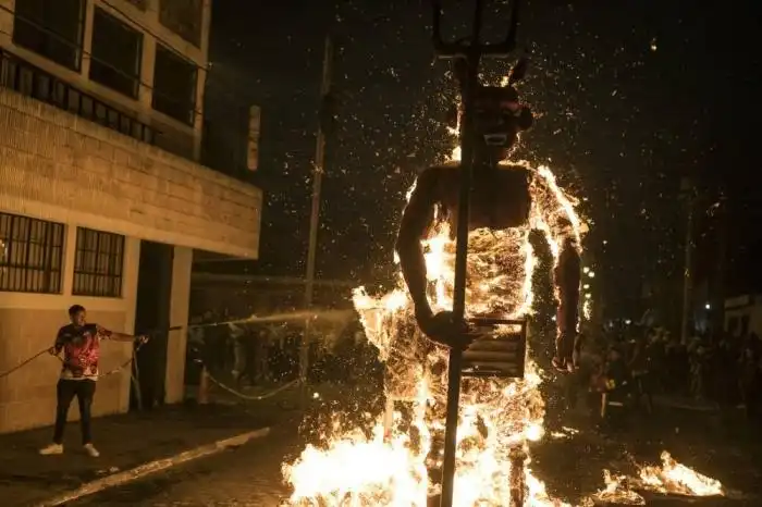 Un hombre intenta apagar el fuego de una figura de diablo quemada durante las celebraciones en honor a la Virgen de la Inmaculada Concepción. /AFP